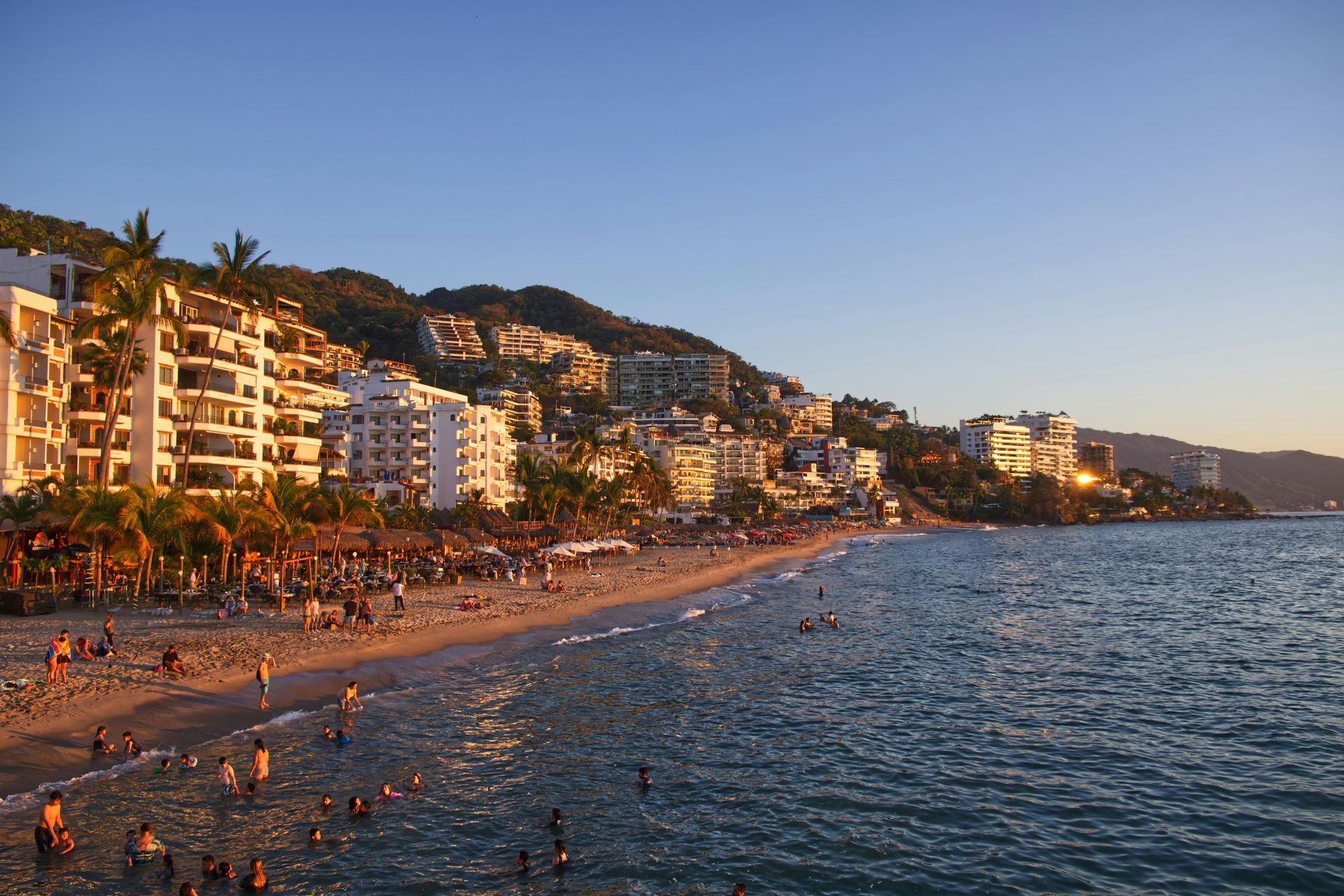 A beach with a lot of people and buildings in the background