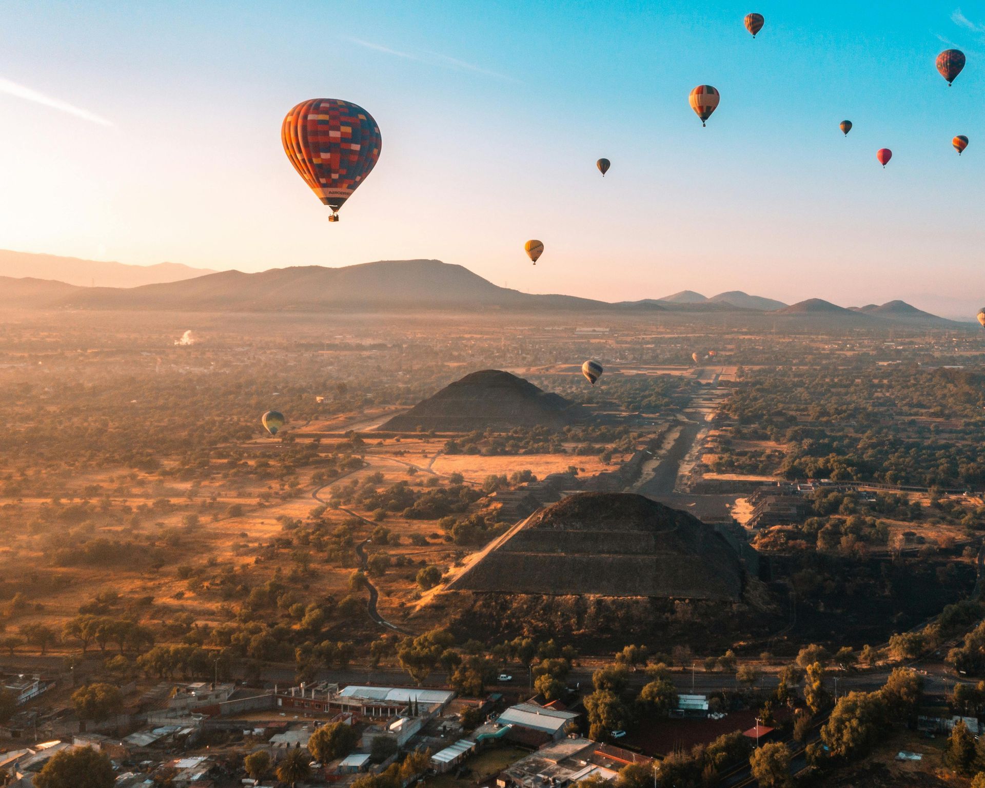 A bunch of hot air balloons are flying over a city.