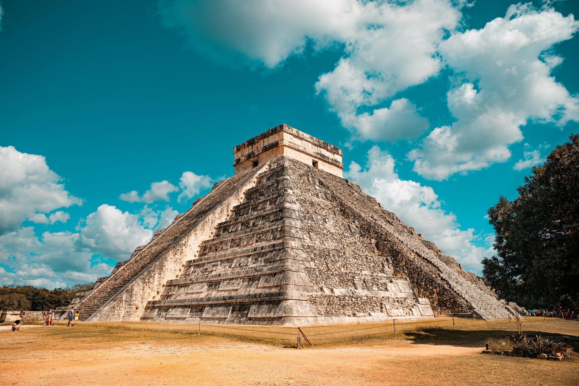 A large stone pyramid with a blue sky and clouds in the background.