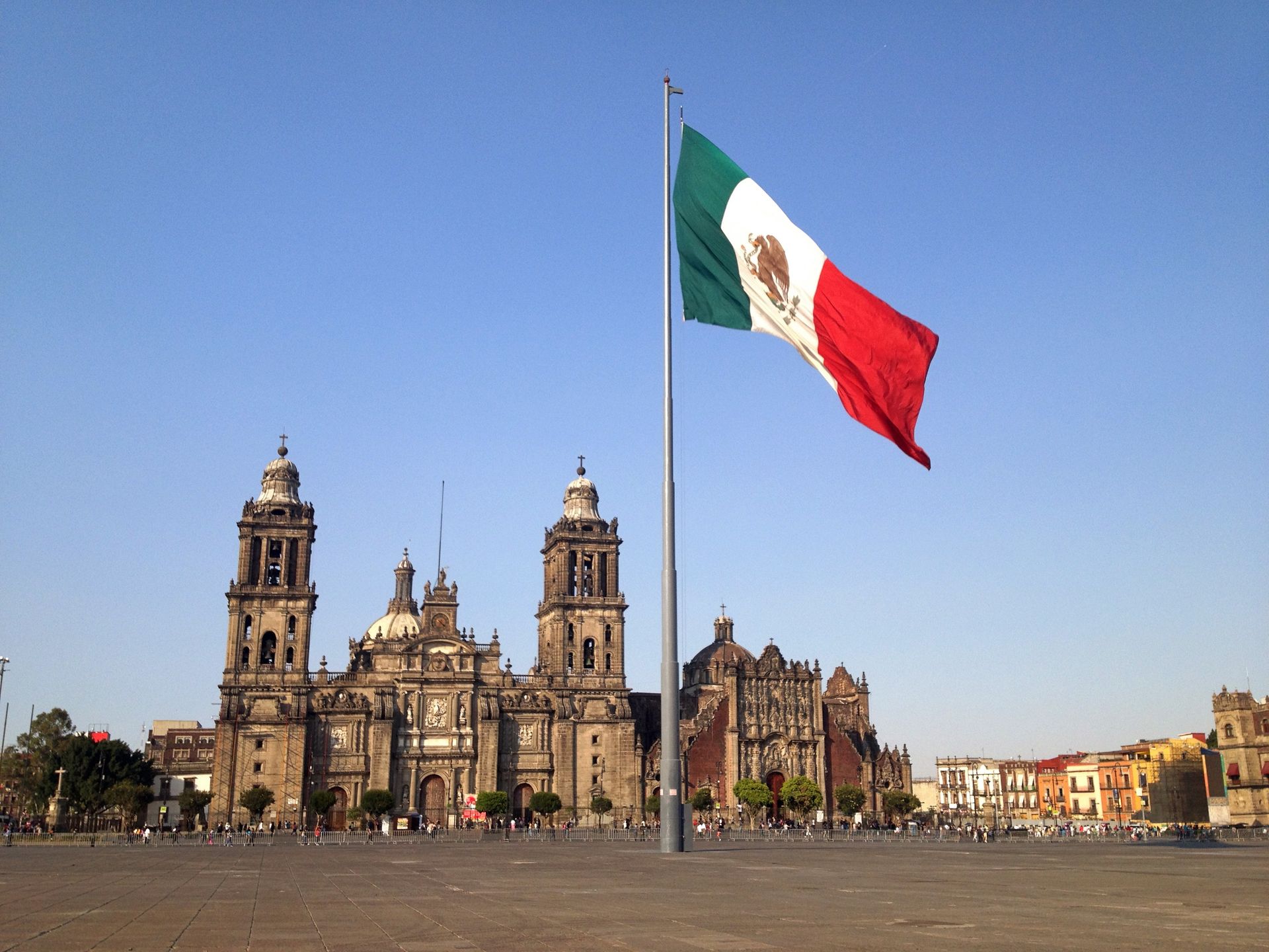 A mexican flag is flying in front of a large building