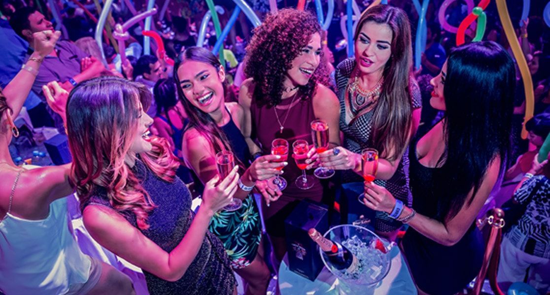A group of women are dancing and drinking champagne at a party.