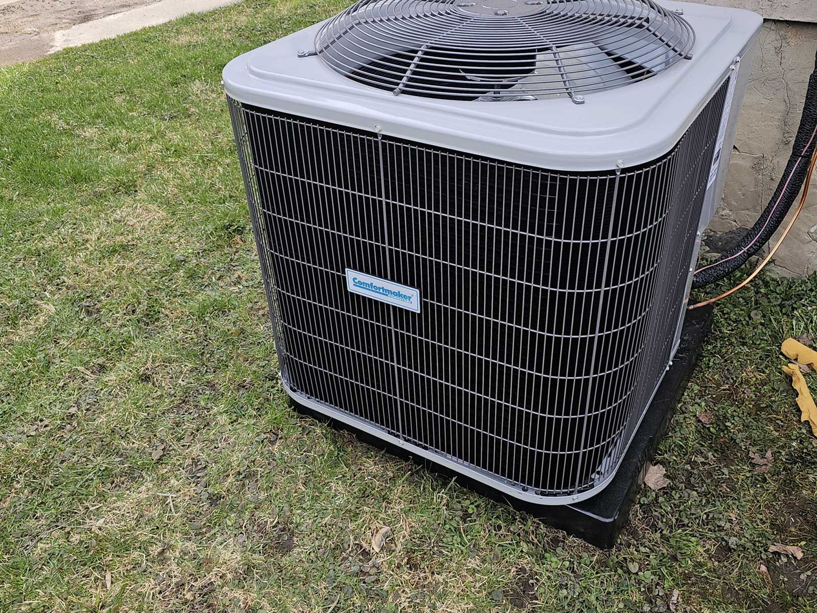 An air conditioner is sitting on top of a lush green lawn.