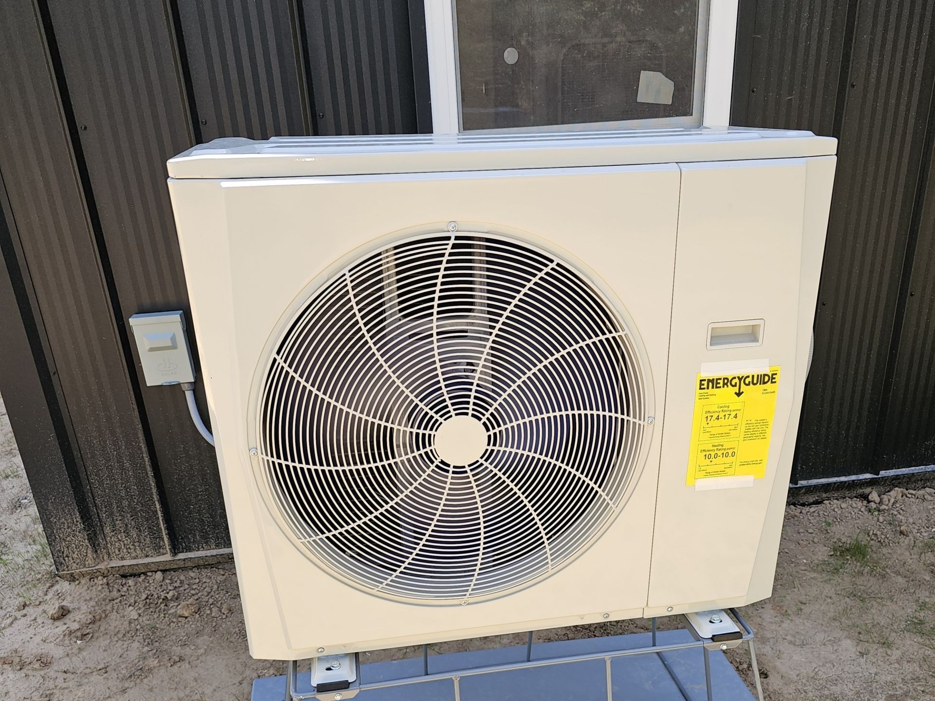 A white air conditioner is sitting on top of a blue tile floor next to a window.