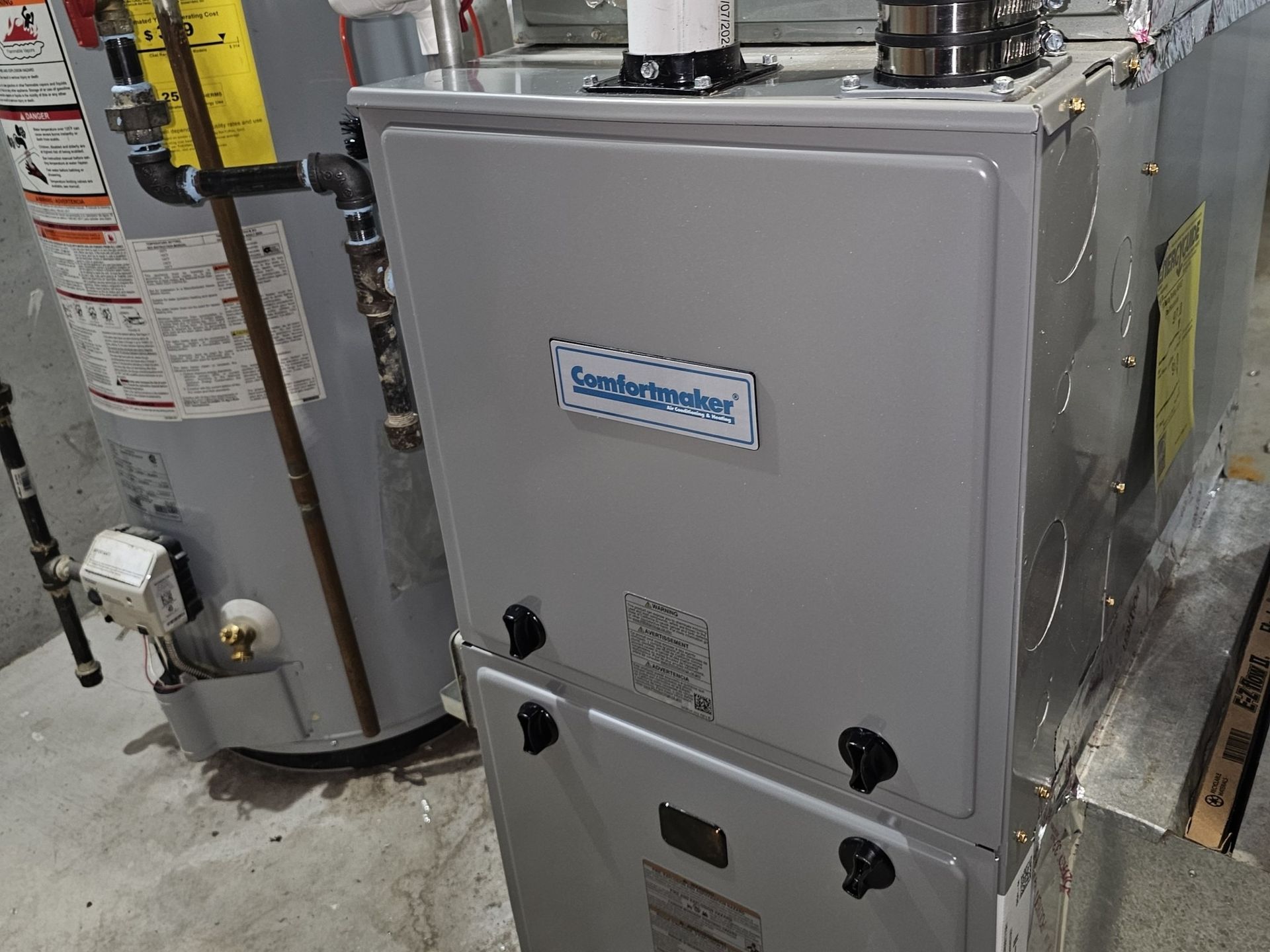 A heating and cooling system is sitting next to a water heater.
