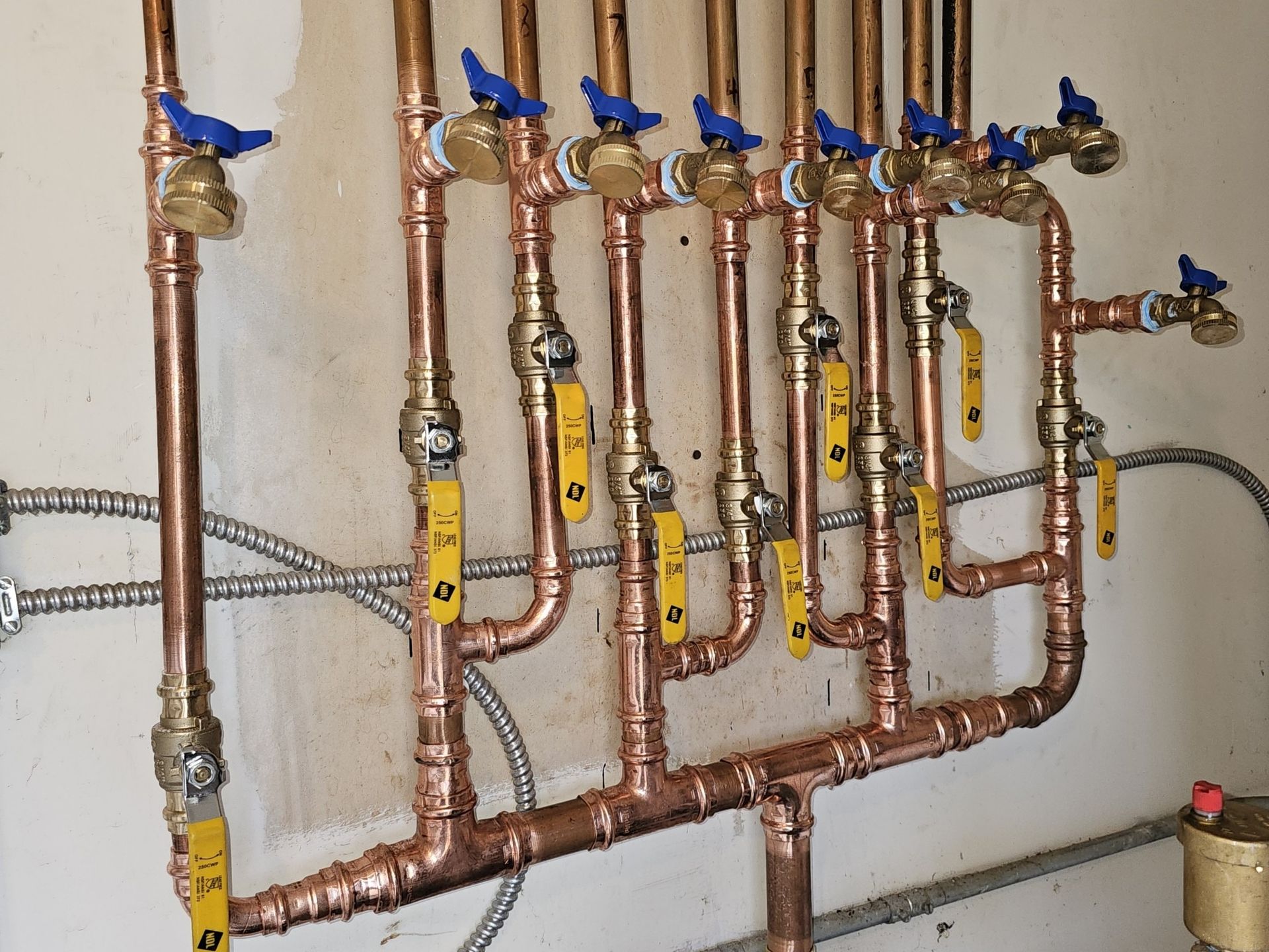 A bunch of copper pipes with blue valves on them