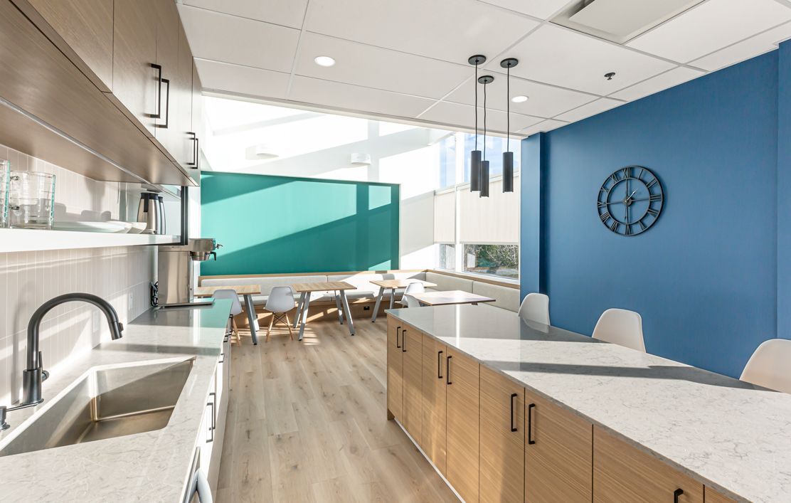 A kitchen with a sink , counters , cabinets and a blue wall.