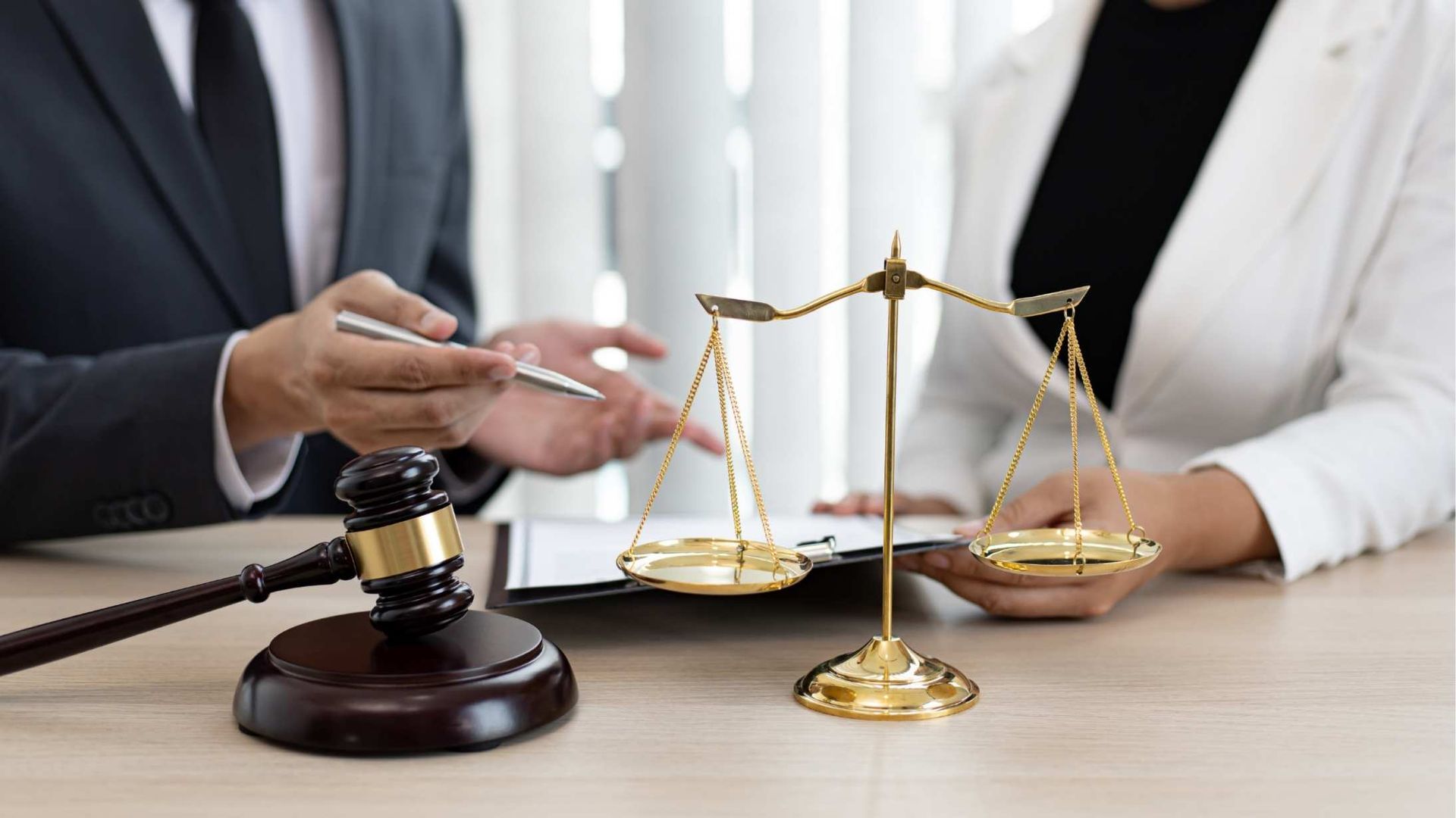 Two lawyers reviewing documents; scales of justice and gavel on the table.