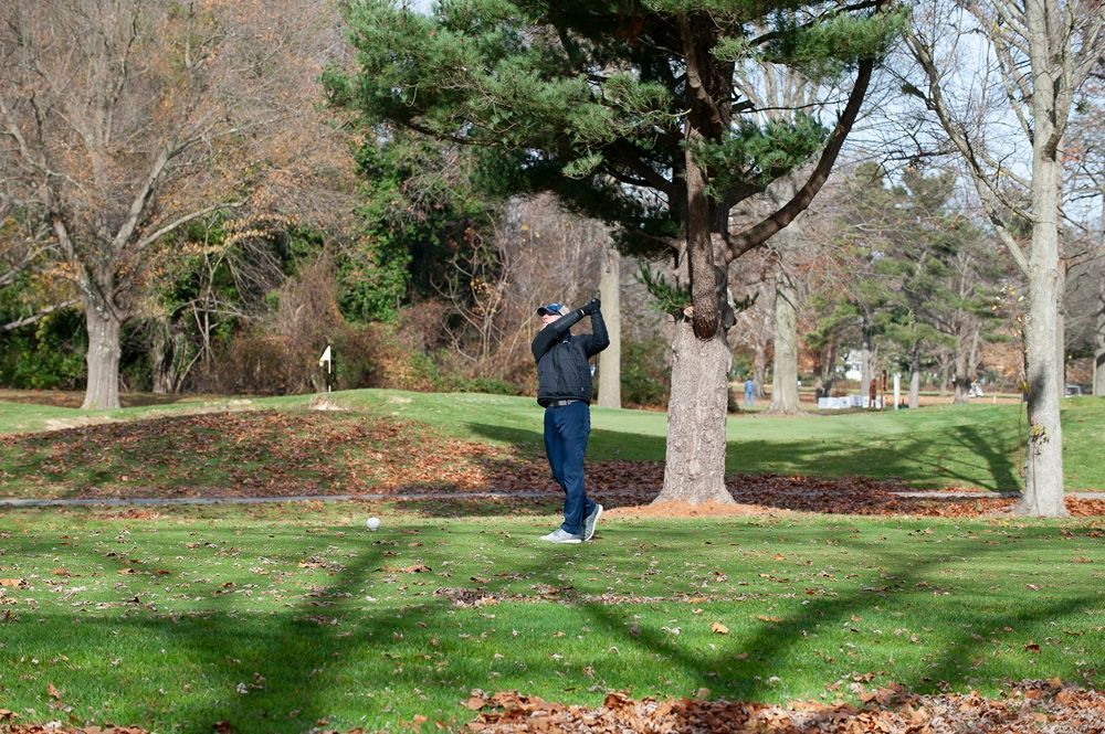 A man is swinging a golf club on a golf course.