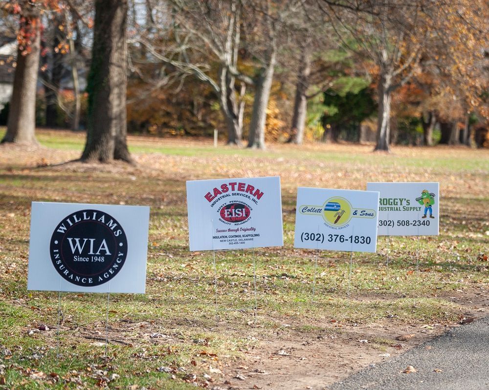 A row of signs in a grassy field one of which says williams wia