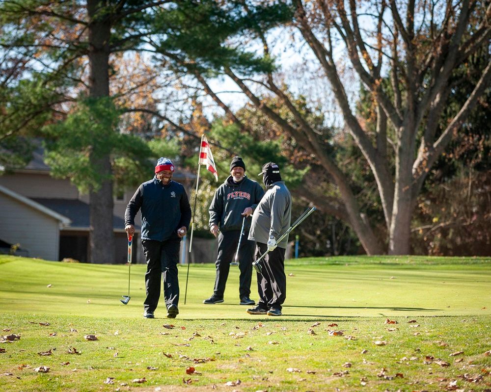 A group of men are standing on a golf course talking to each other.