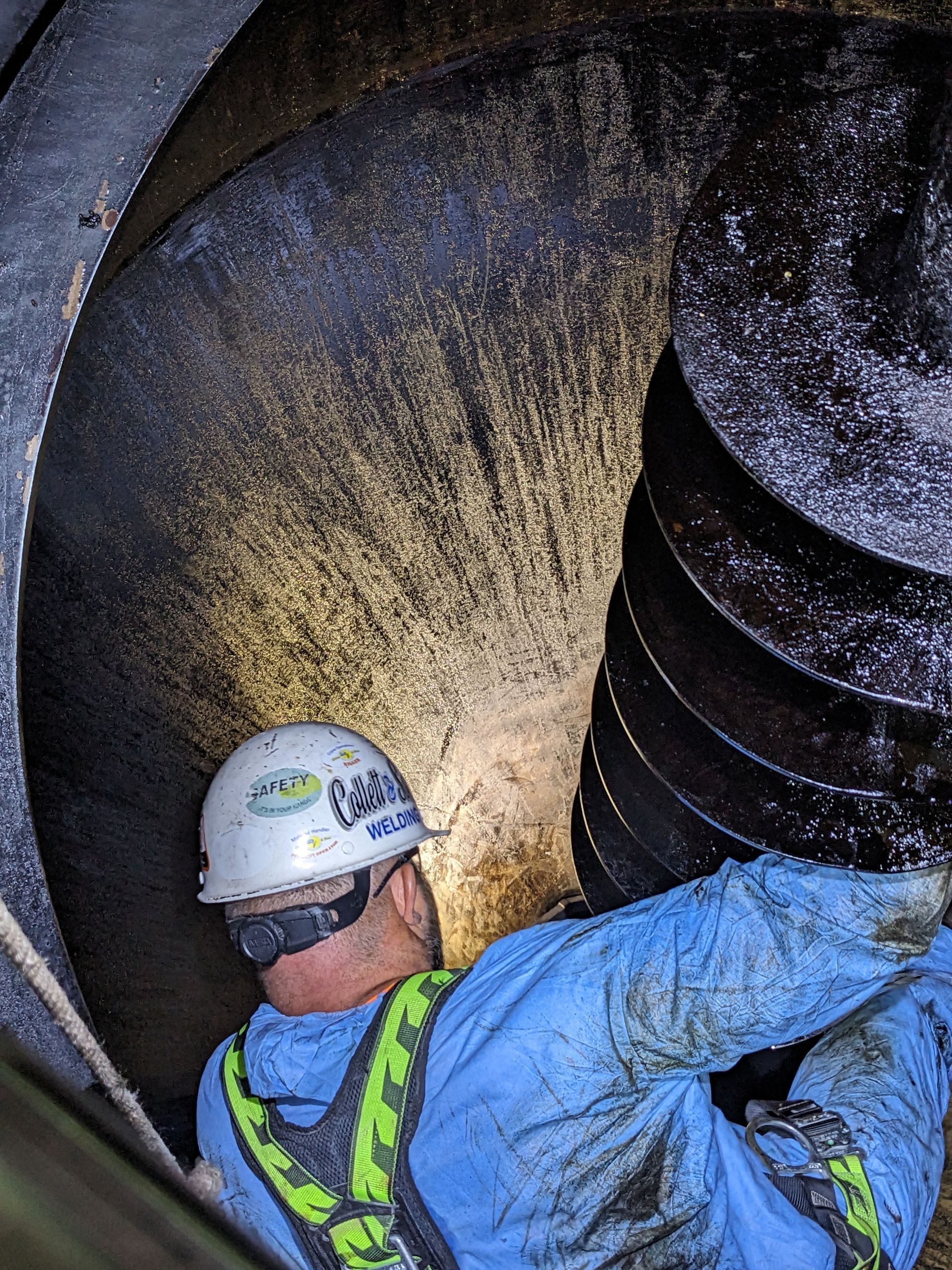 A man wearing a hard hat is working on a machine