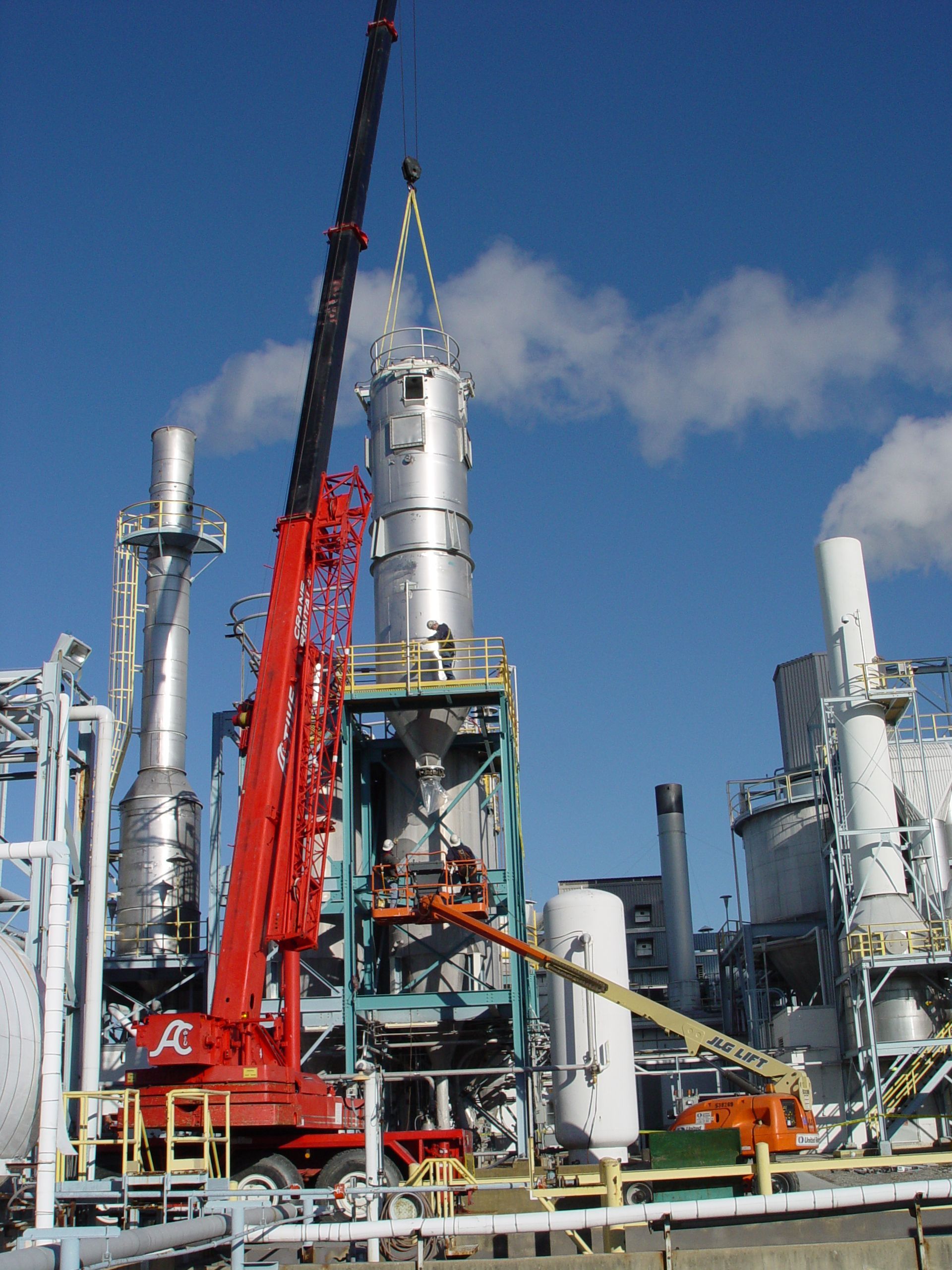 A red crane is lifting a tower in a factory