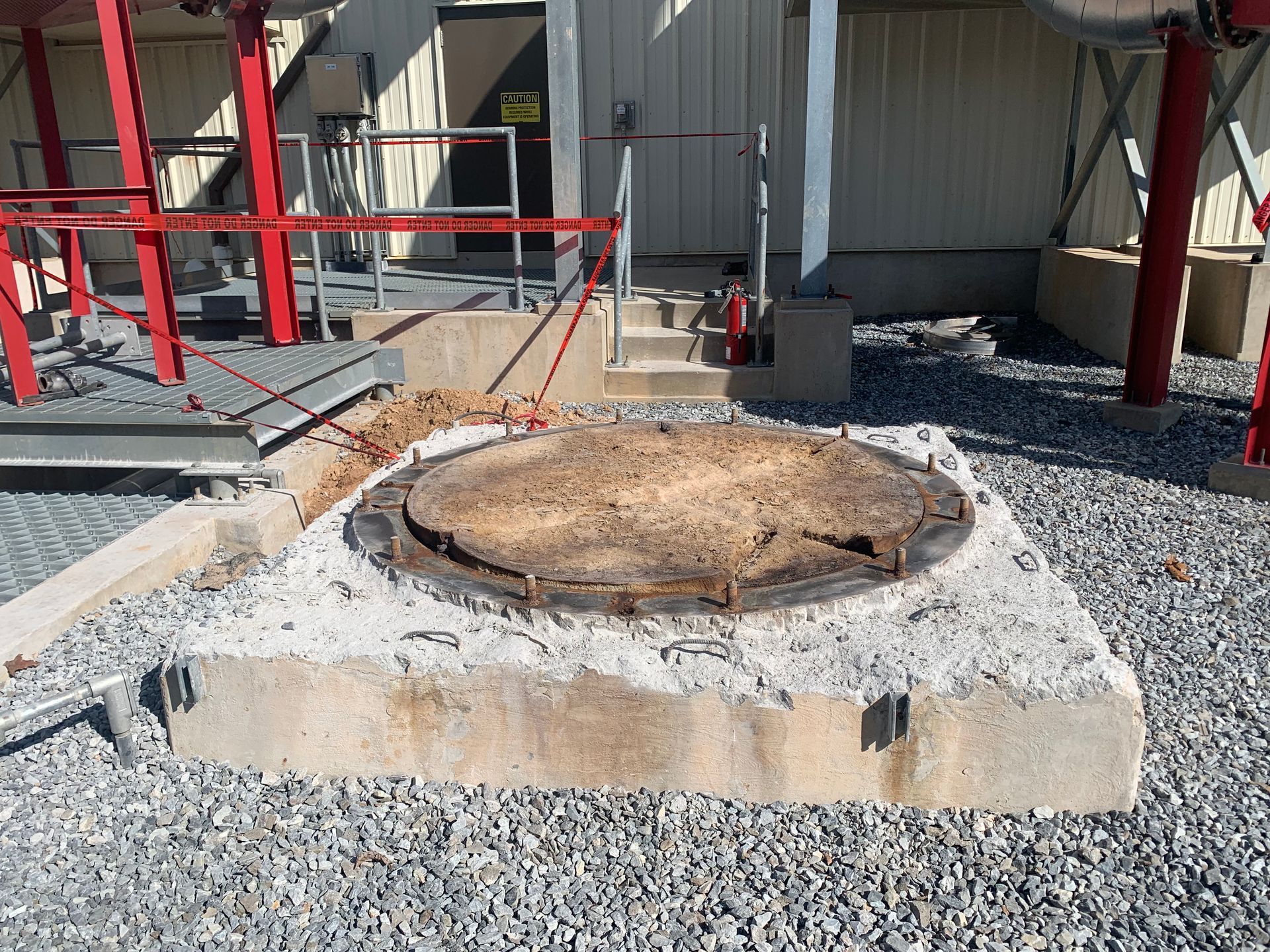 A manhole cover is sitting on top of a gravel area in front of a building
