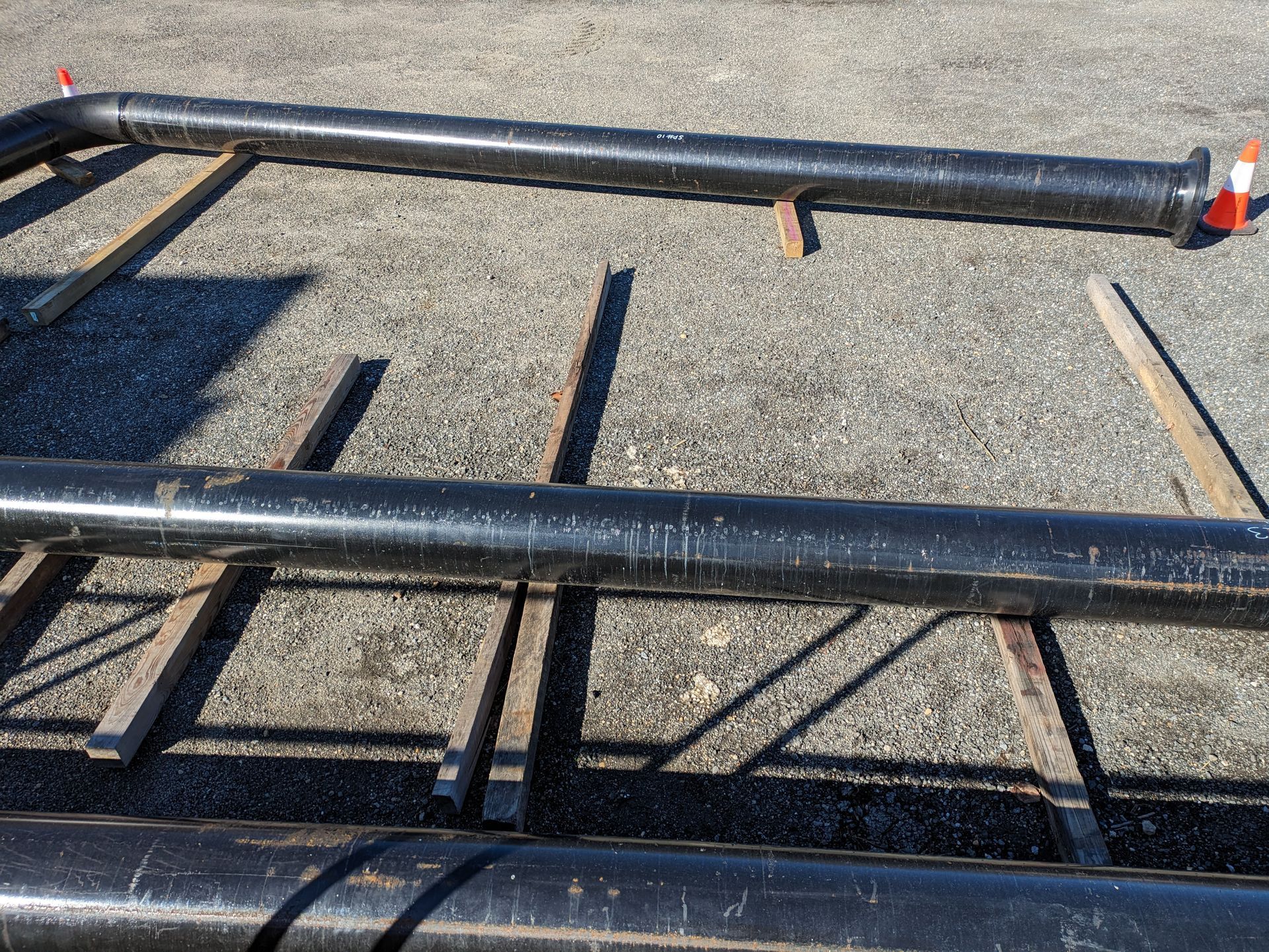 A bunch of black pipes are laying on the ground