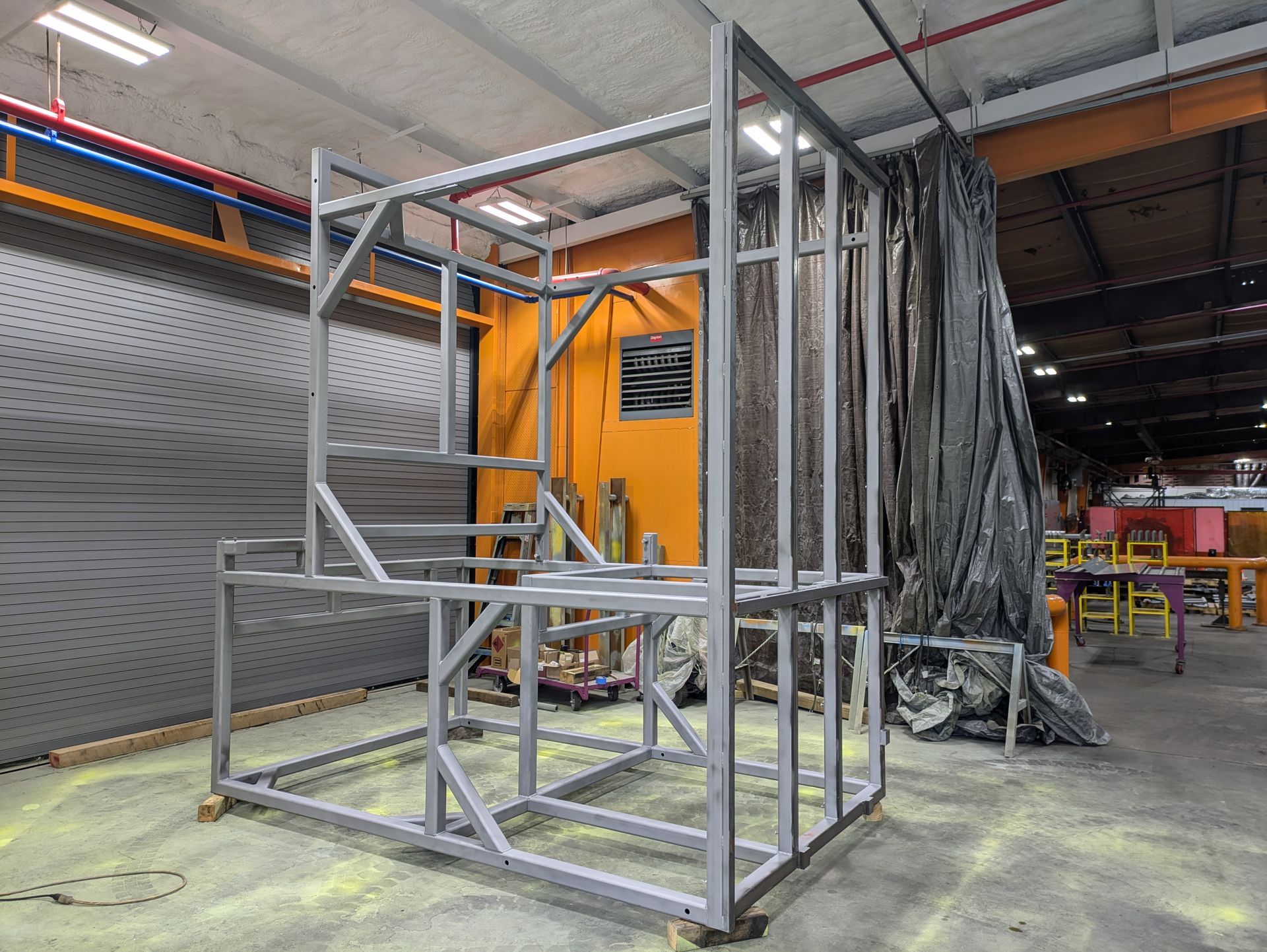 A metal frame is sitting on the floor in a factory.