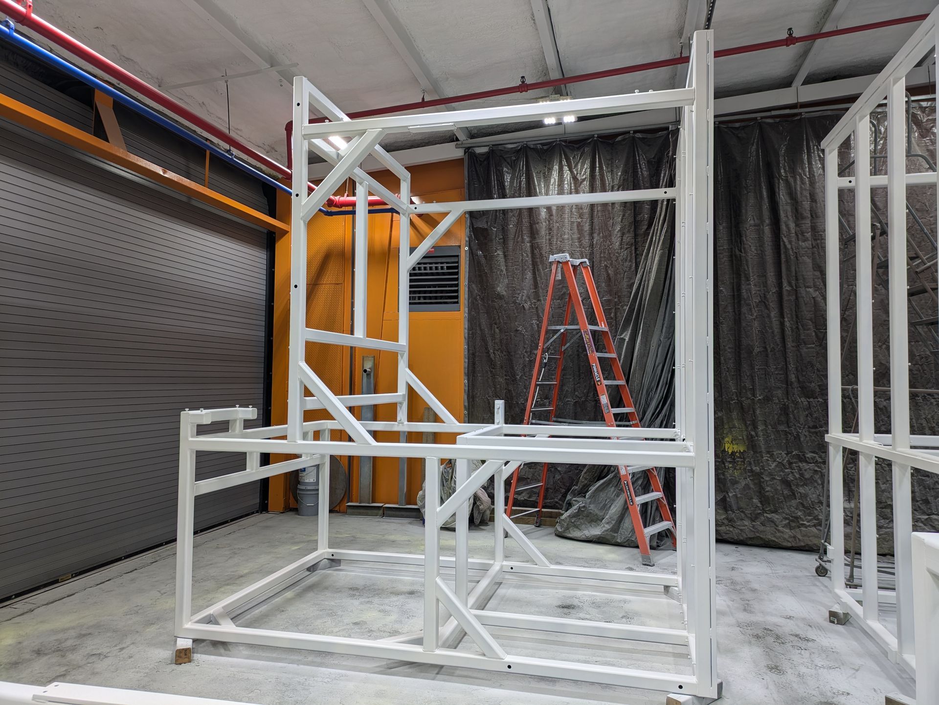 A large white metal structure is sitting in a room with a ladder.