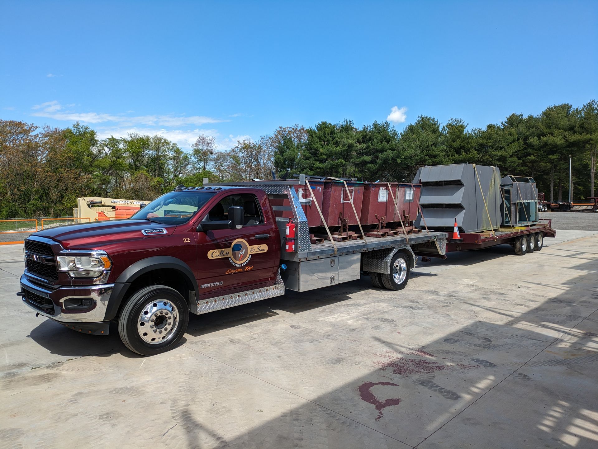 A red ram truck is towing a trailer filled with concrete blocks.