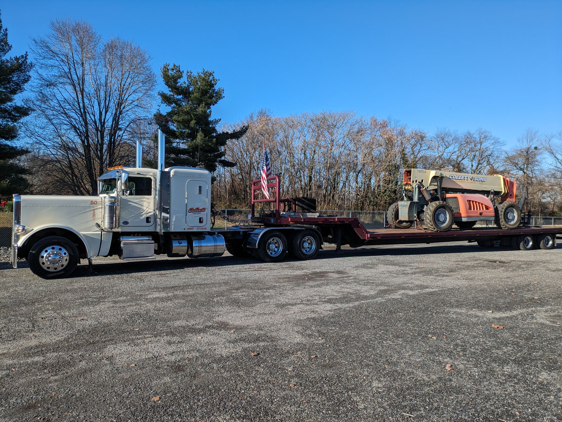 A semi truck is carrying a forklift on a flatbed trailer.