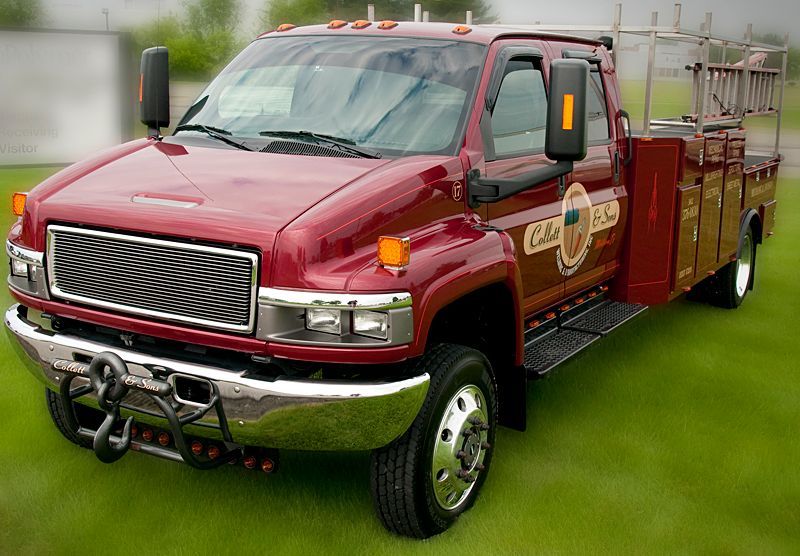 A red tow truck is parked on a lush green field.