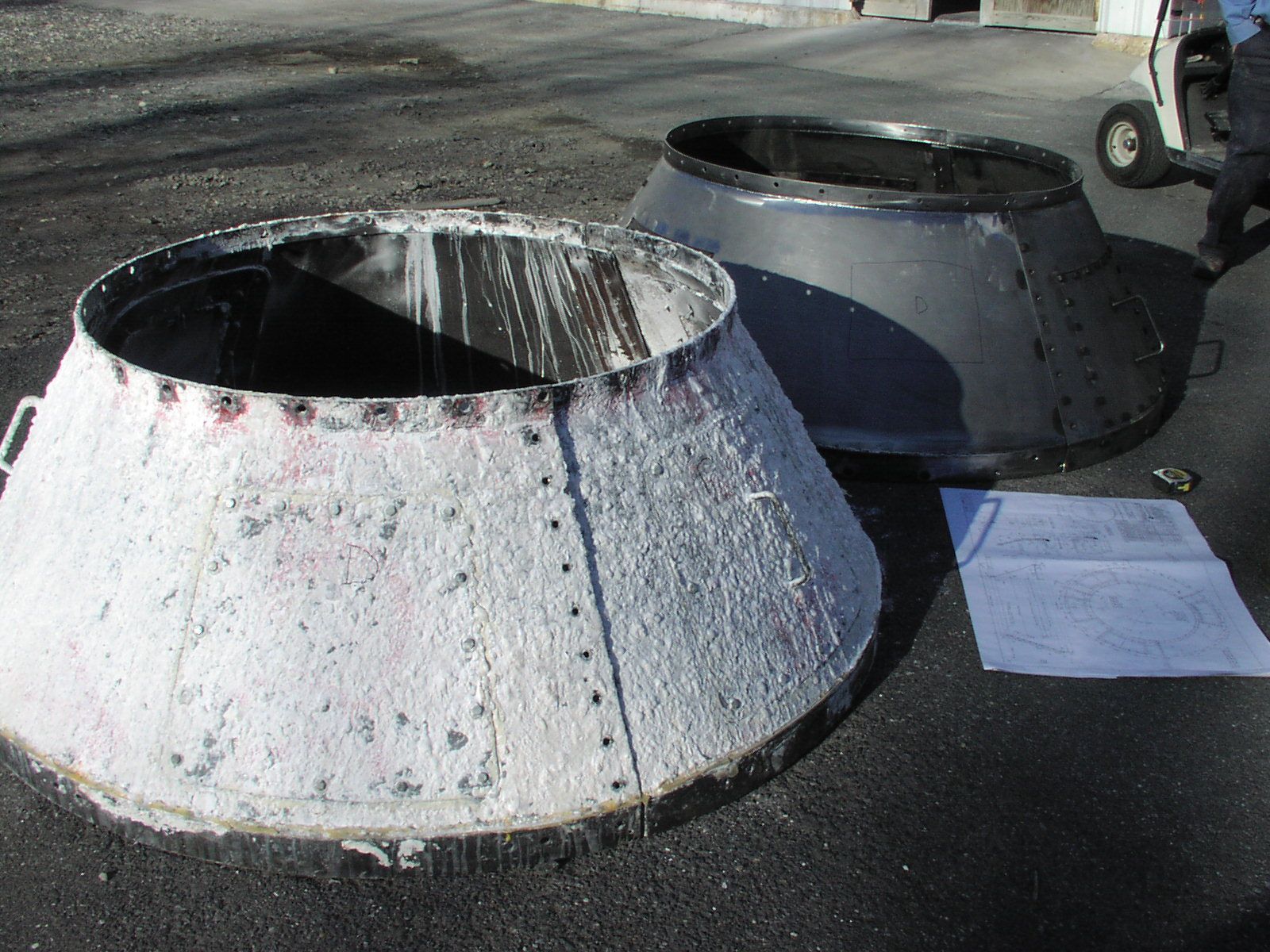 Two metal cones are sitting on the ground next to a piece of paper