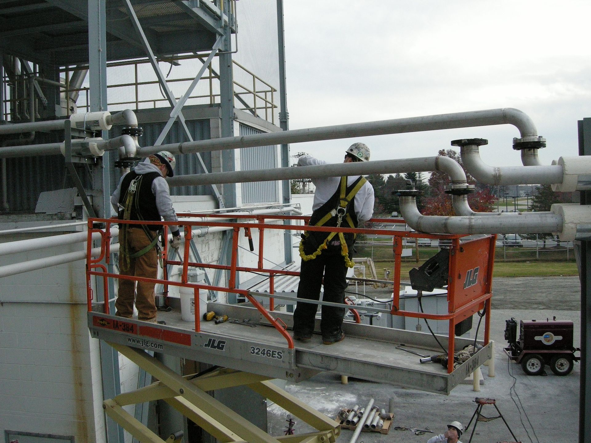 Two men standing on a platform that says jlg on it