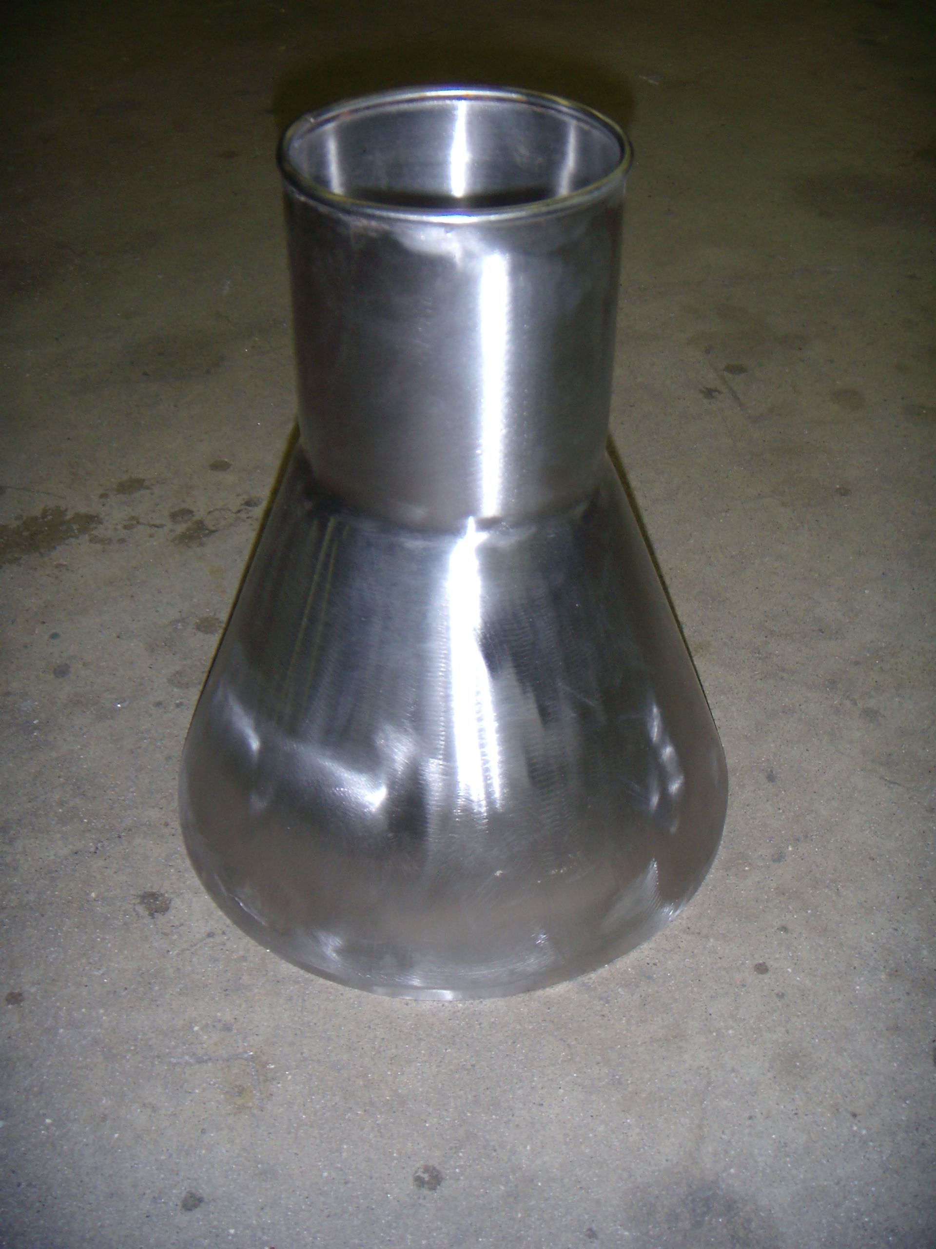 A metal cone is sitting on a concrete surface.