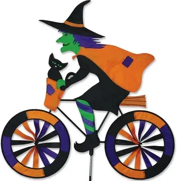 A witch is riding a bike with a cat in her basket