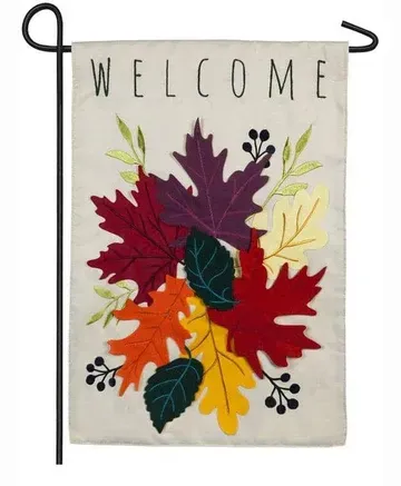 A welcome flag with autumn leaves on it