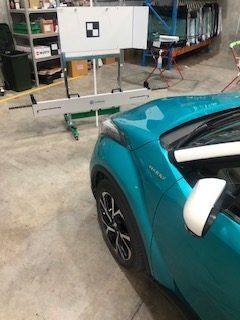 A Blue Car is Parked in a Garage Next to a White Board — Morayfield Autoglass in Caboolture South, QLD