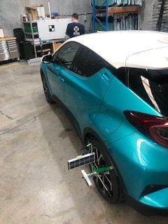A Blue and White Car is Being Adjusted in a Garage — Morayfield Autoglass in Caboolture South, QLD