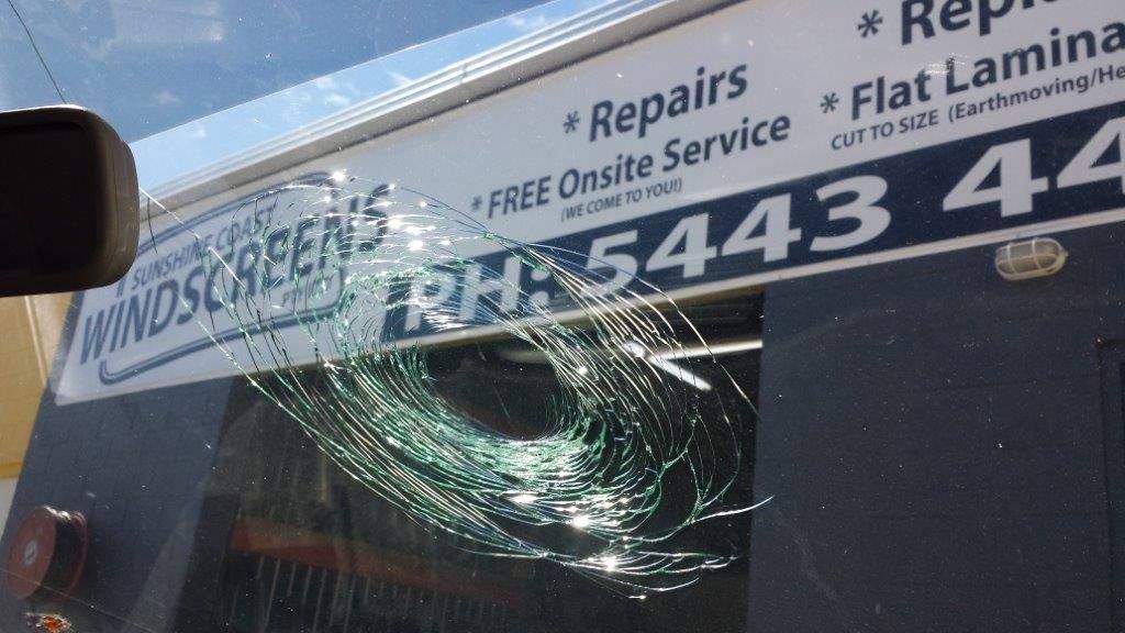 Shattered Car Windshield With Visible Cracks, In Front Of A Windscreen Repair Shop Sign With Phone Number  — Morayfield Autoglass in Caboolture South, QLD
