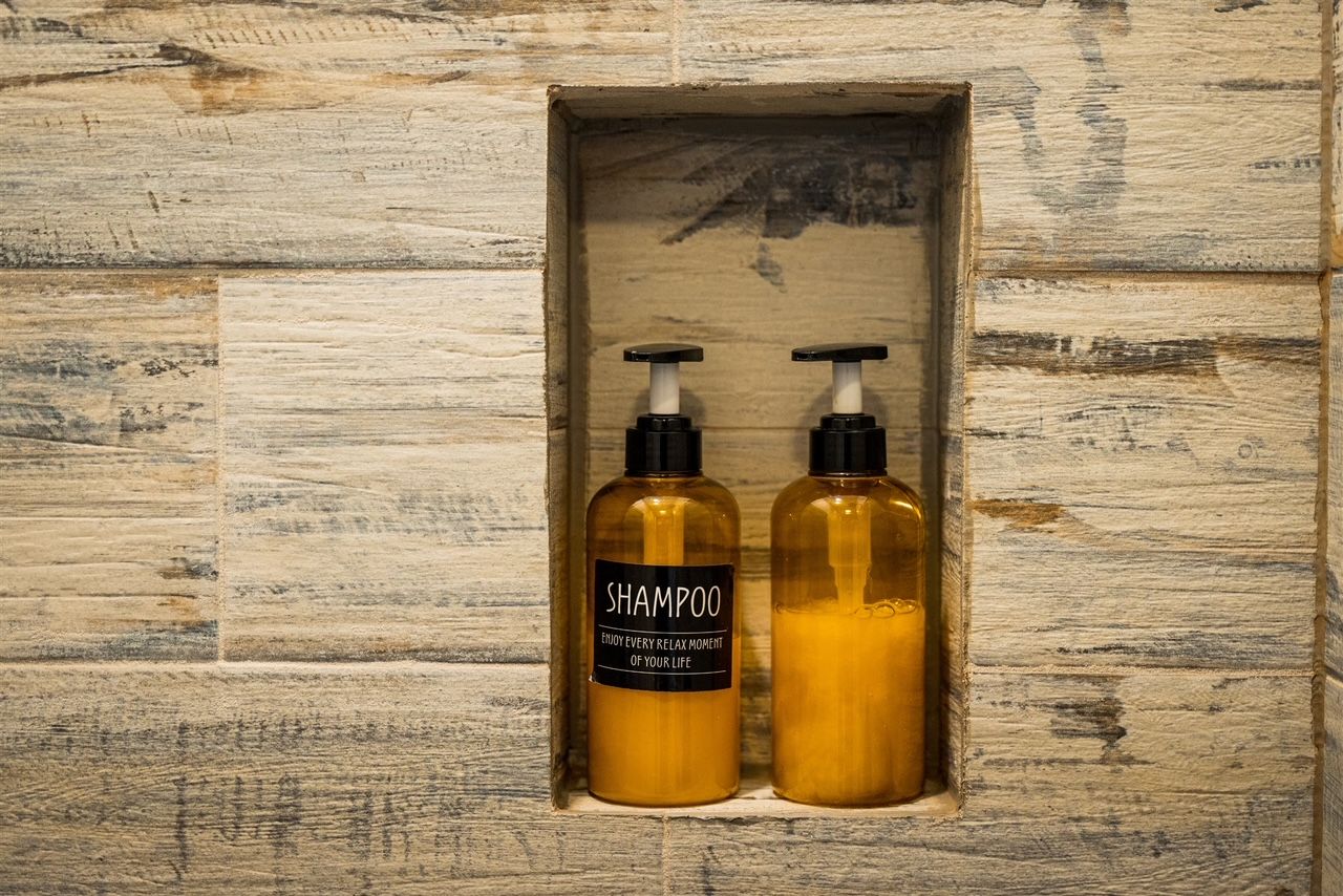 two bottles of shampoo and lotion are sitting in a niche on a wooden wall .