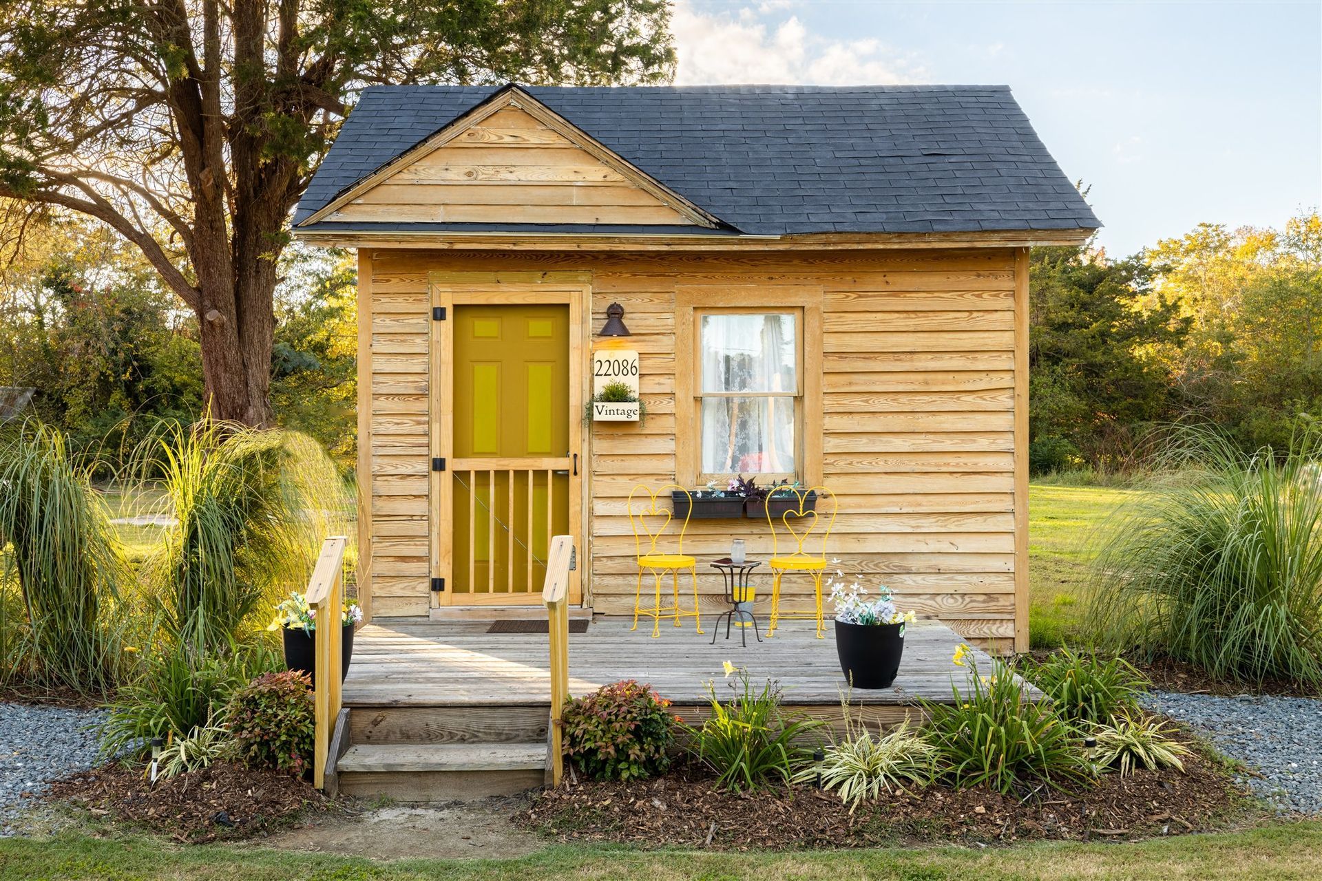 a small wooden house with a yellow door is sitting in the middle of a field .