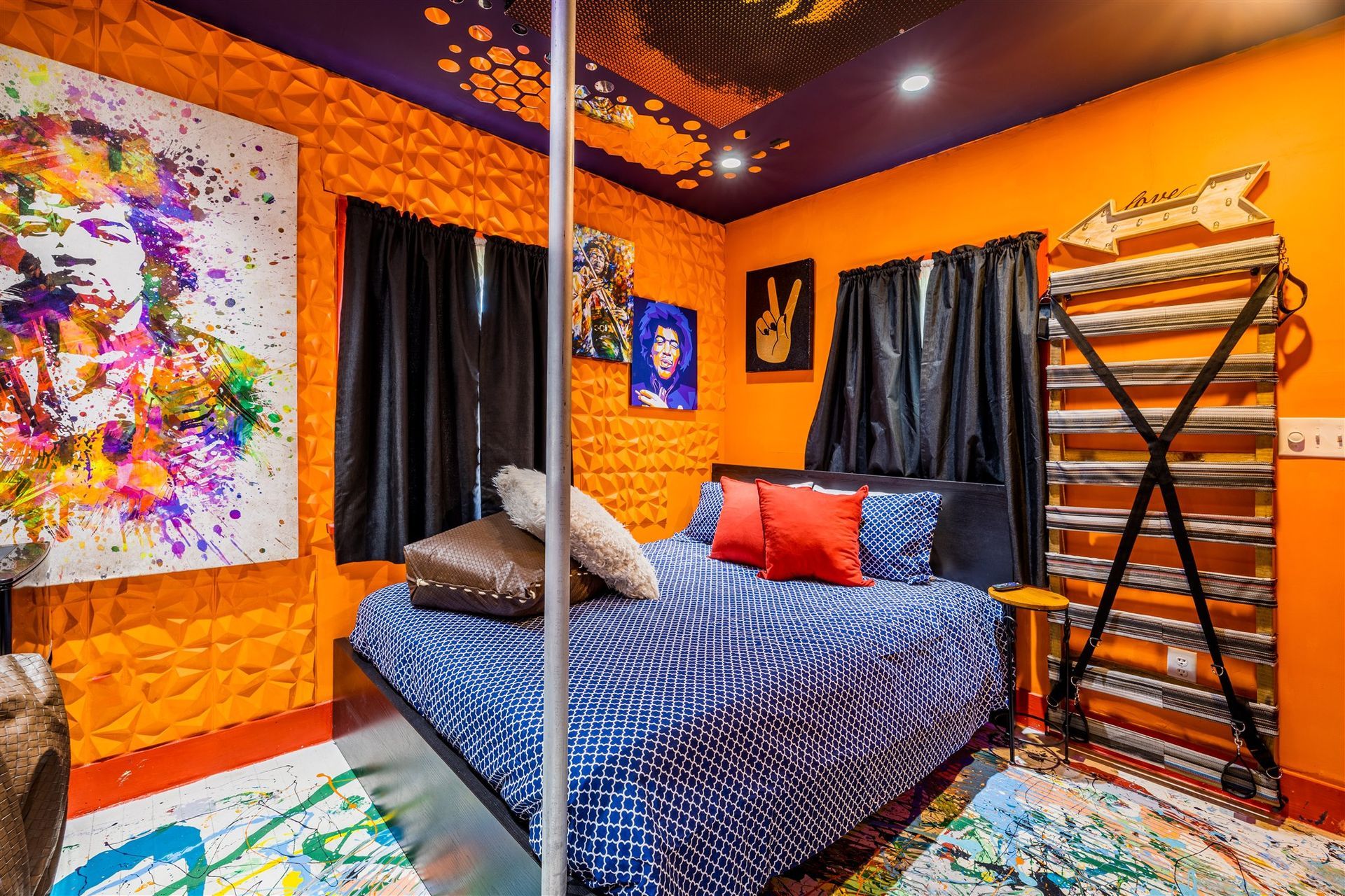 a bedroom with a bed , pole , paintings on the wall and ceiling .