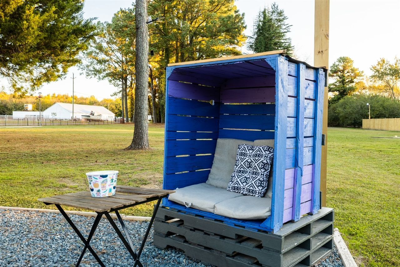 a blue and purple chair made out of wooden pallets is sitting next to a table .