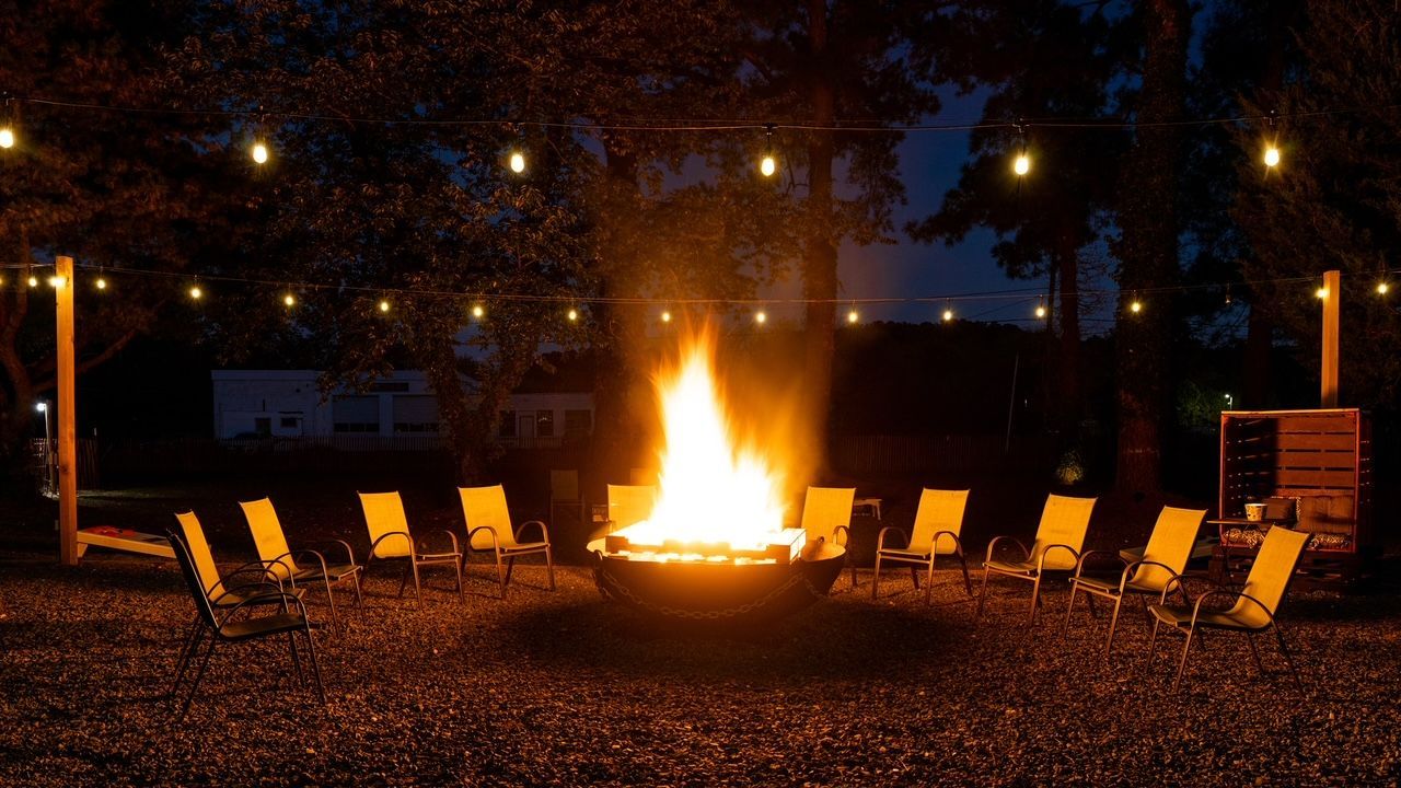 a group of chairs are sitting around a fire pit at night .