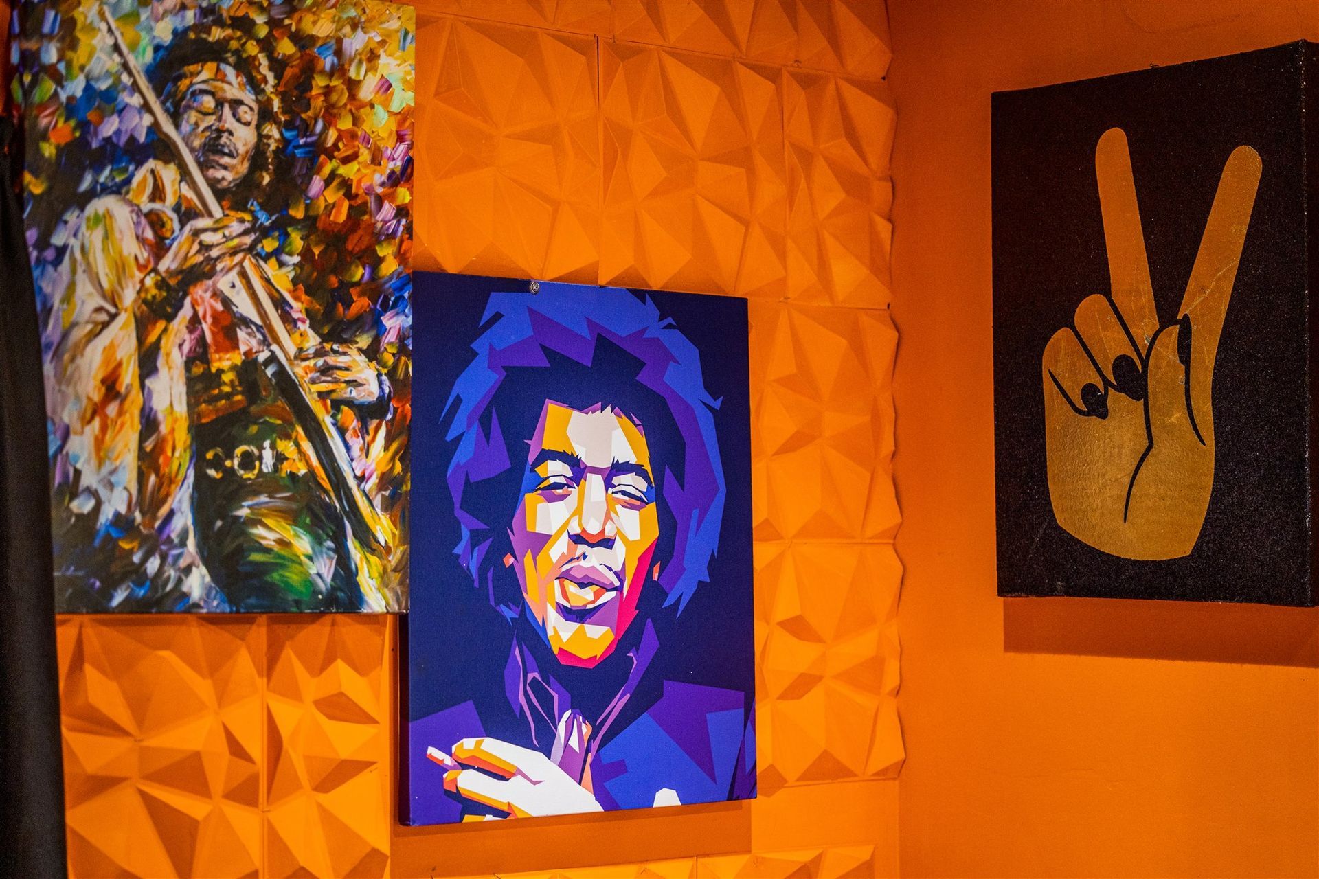a painting of jimi hendrix is hanging on a wall next to a peace sign .
