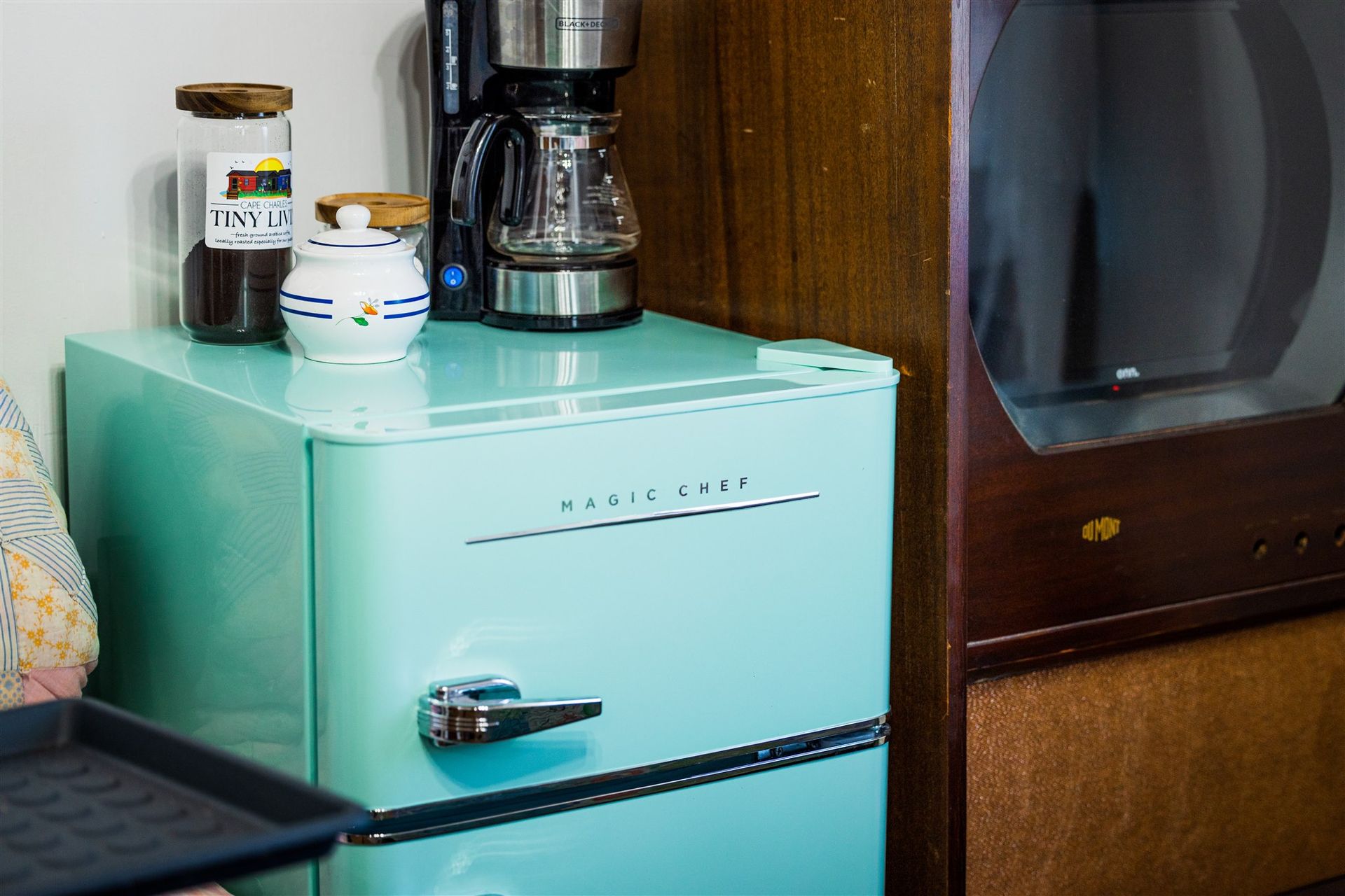 a blue refrigerator is sitting next to a microwave and a coffee maker .