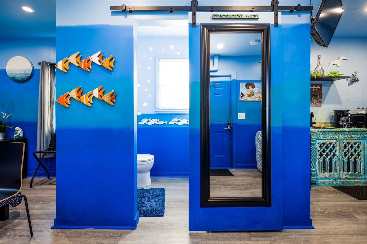 a bathroom with blue walls , a toilet , and a mirror .