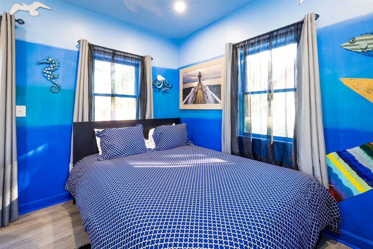 a bedroom with blue walls and a bed with a blue comforter .