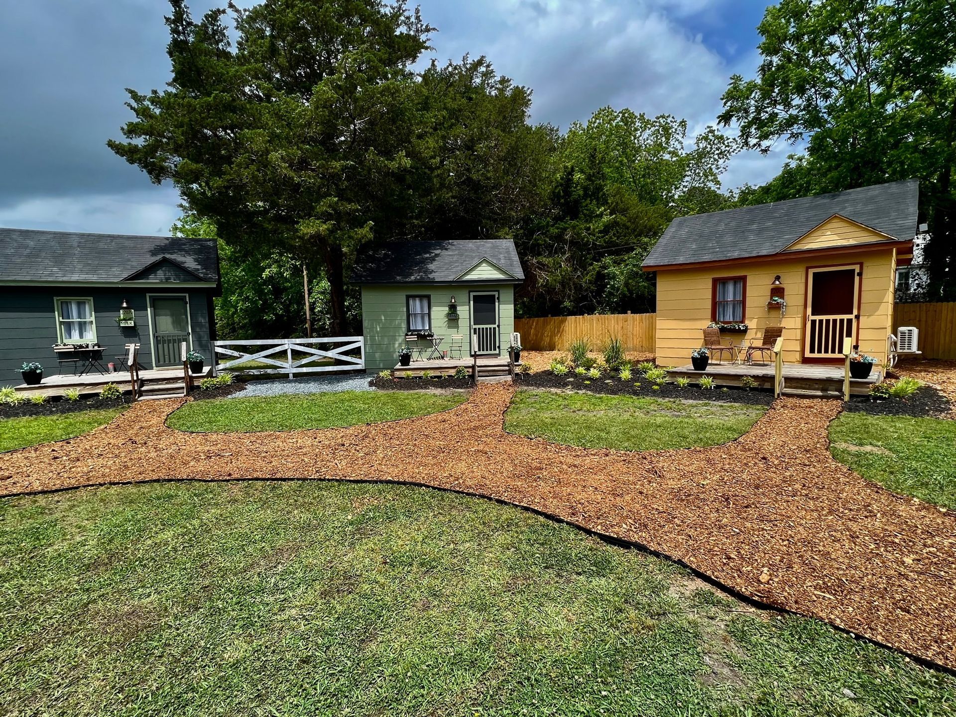 Three small houses are sitting next to each other in a grassy yard.