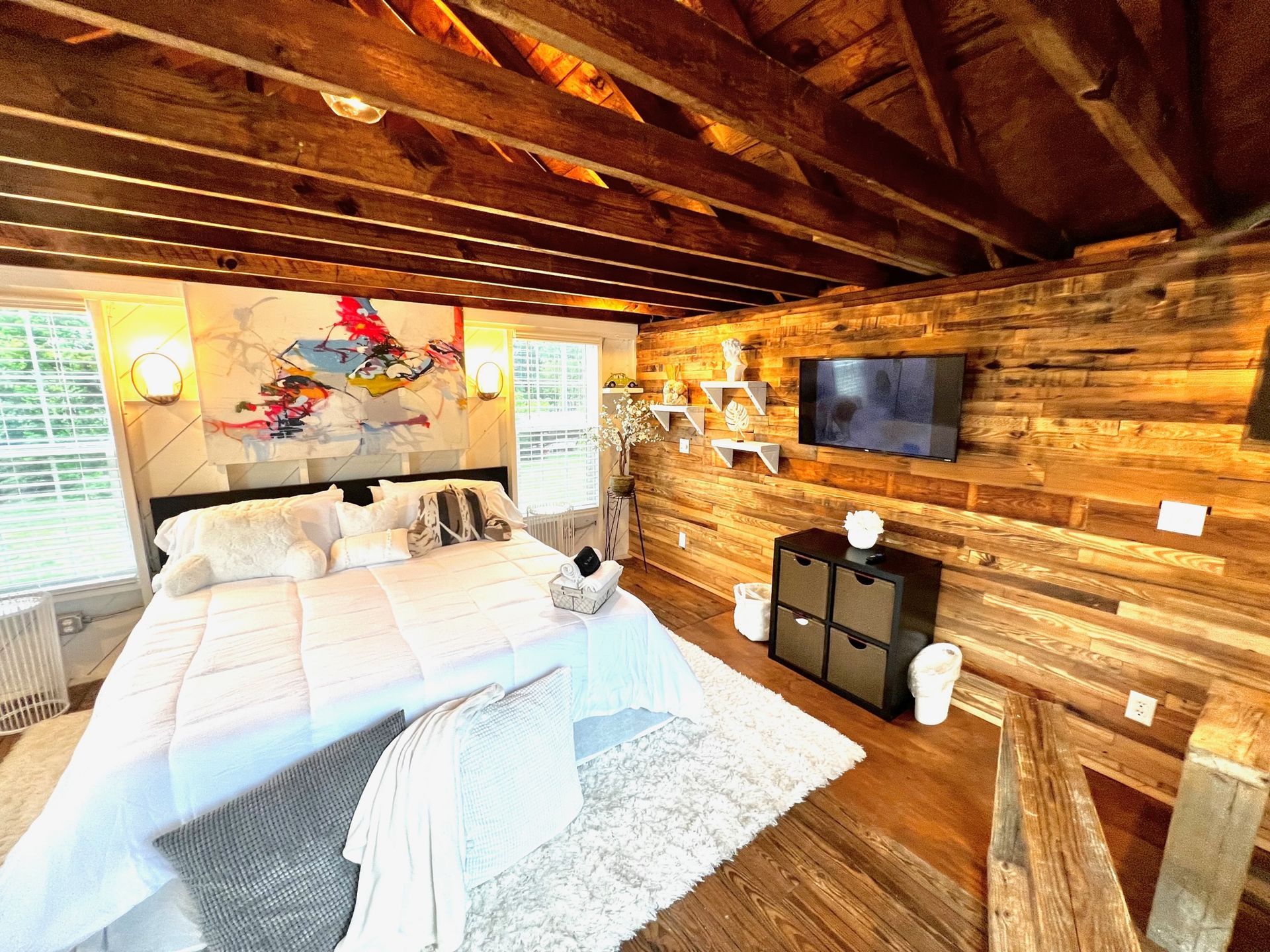 a bedroom with a large bed and a flat screen tv on the wall .