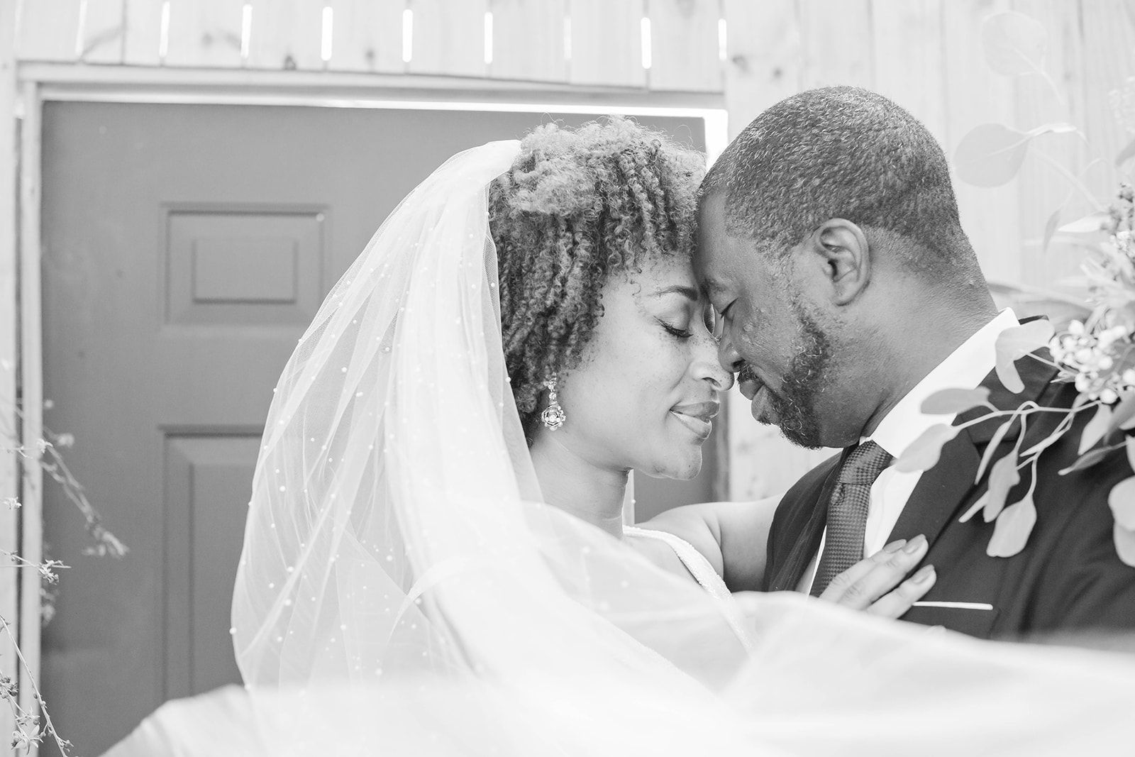 a black and white photo of a bride and groom looking into each other 's eyes .