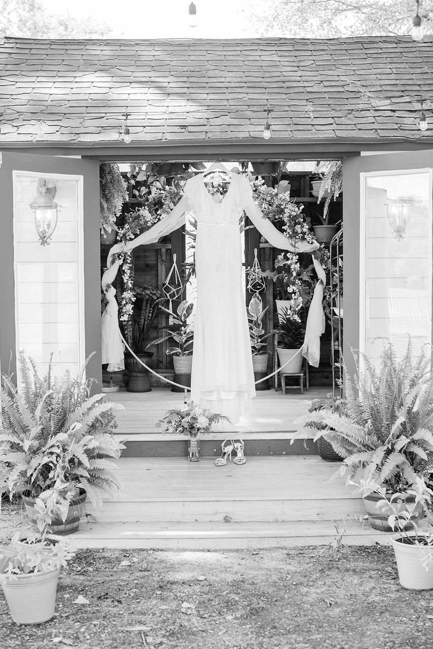 a black and white photo of a woman in a white dress standing in front of a building .