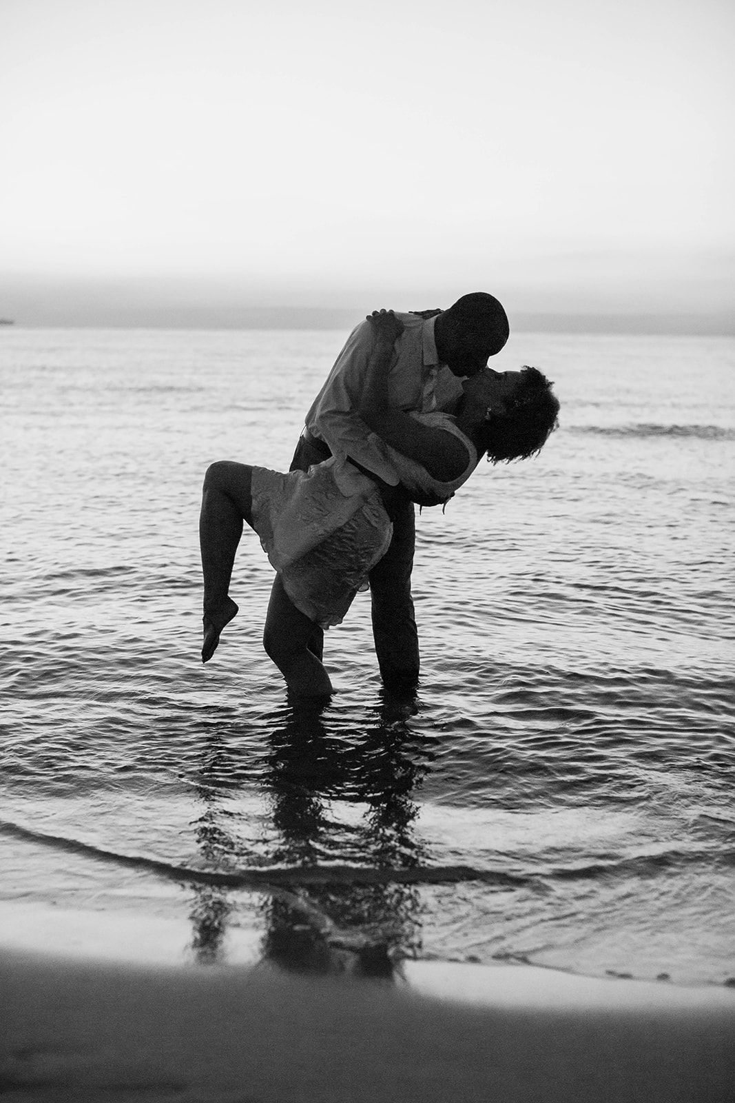 a man is holding a woman in his arms on the beach .