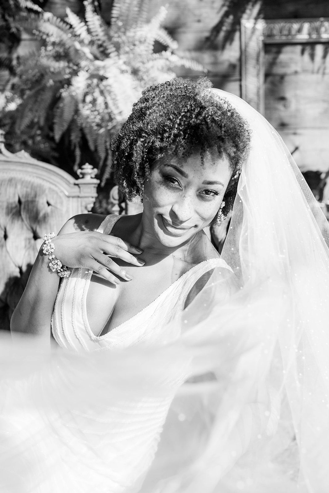 a black and white photo of a bride in a wedding dress and veil .
