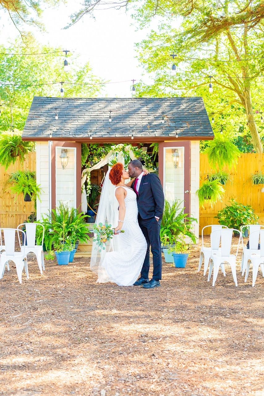 a bride and groom are kissing in front of a shed .