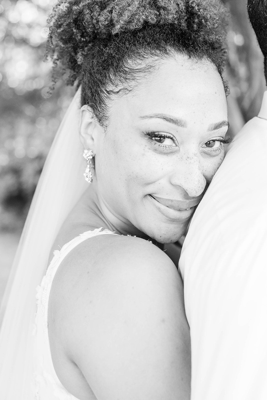 a black and white photo of a bride hugging her groom .