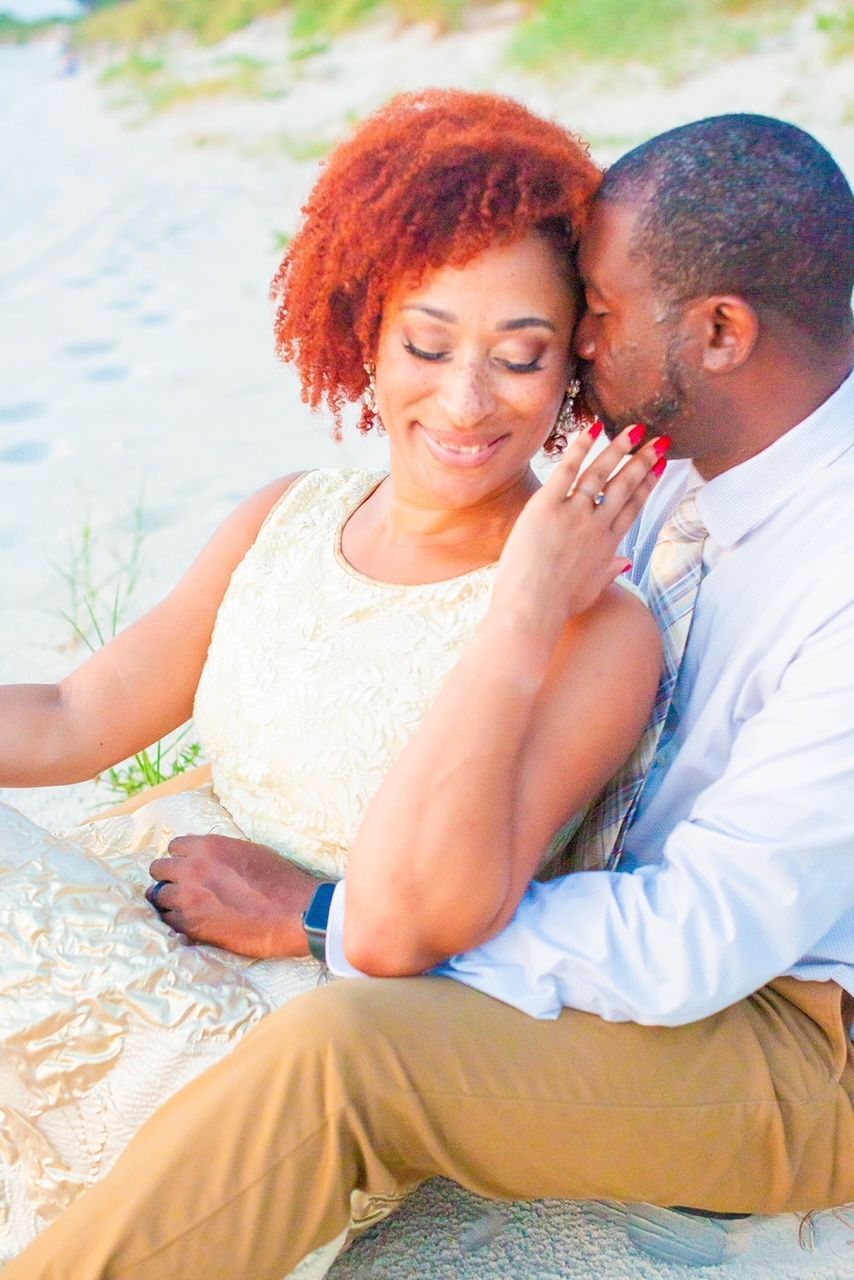 a man is kissing a woman on the forehead on the beach .