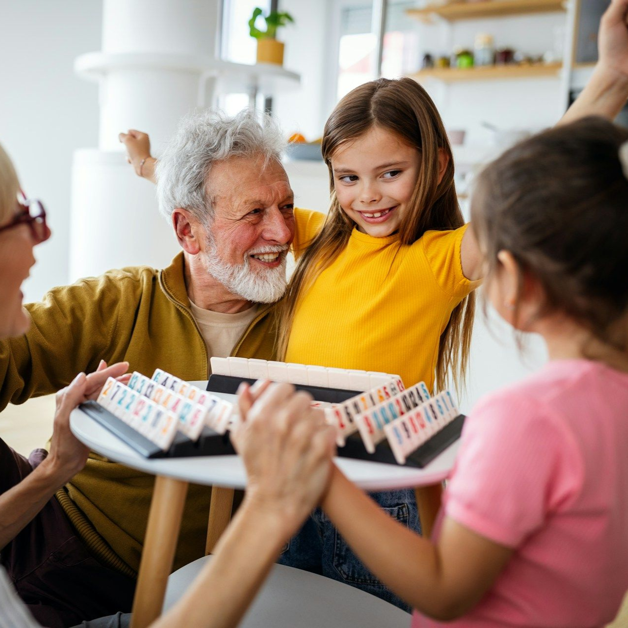 Grandparents and granddaughters playing a board game together, smiling with joy.